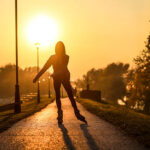 Young woman on roller skates skating into sunset. About 20 years old, unrecognizable woman.