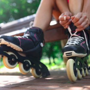 Young woman puts on roller skates in park. Sports and walking concept