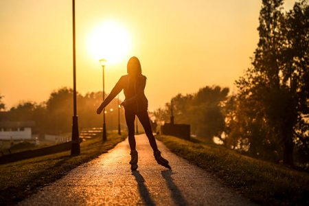 Young woman on roller skates skating into sunset. About 20 years old, unrecognizable woman.